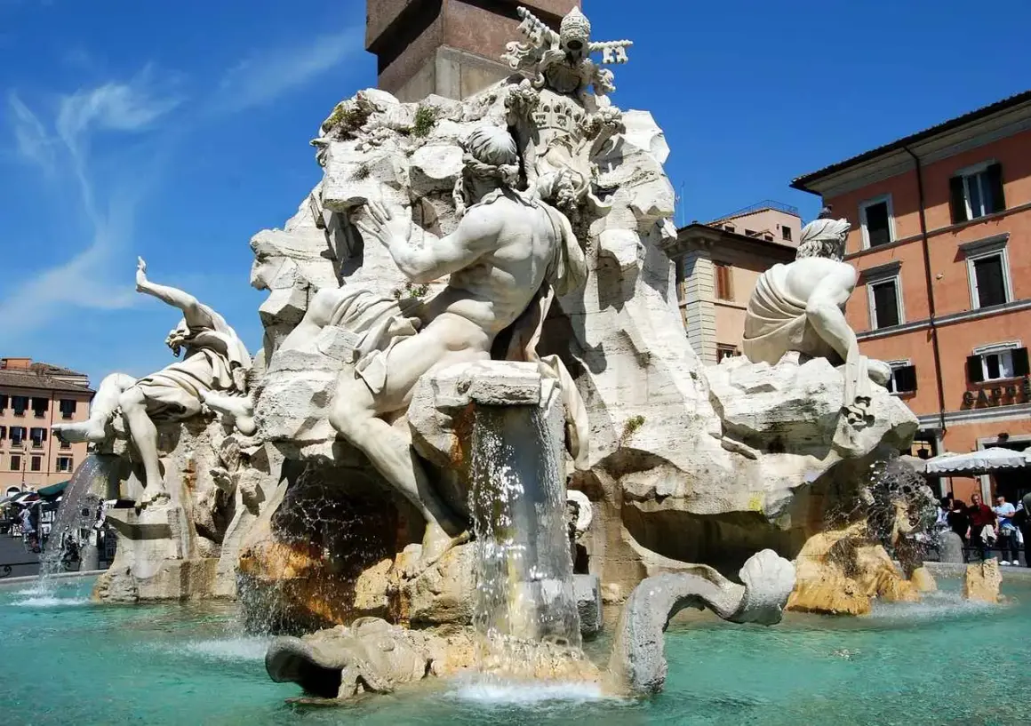 La Fontana dei Quattro Fiumi di Bernini, con le sue maestose statue che rappresentano i fiumi del mondo, zampilla sotto il cielo azzurro di Roma.