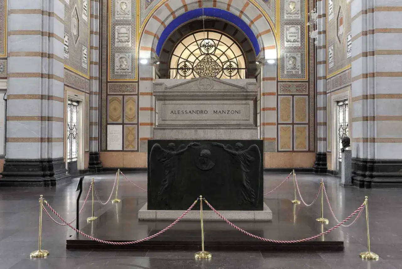 La tomba di Manzoni, imponente e decorata, con un bassorilievo di angeli e un busto.