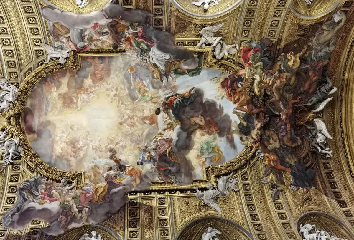 Soffitto affrescato della chiesa del Ges&ugrave;, un tripudio di angeli e figure celesti che sembrano fluttuare tra nuvole dorate e scure.