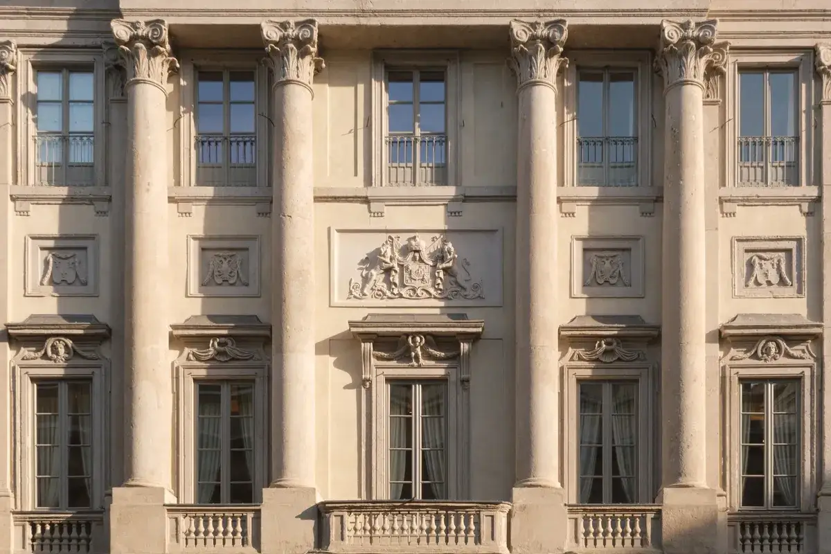 Facciata del Palazzo Belgioioso con colonne corinzie, finestre eleganti e un bassorilievo araldico centrale.