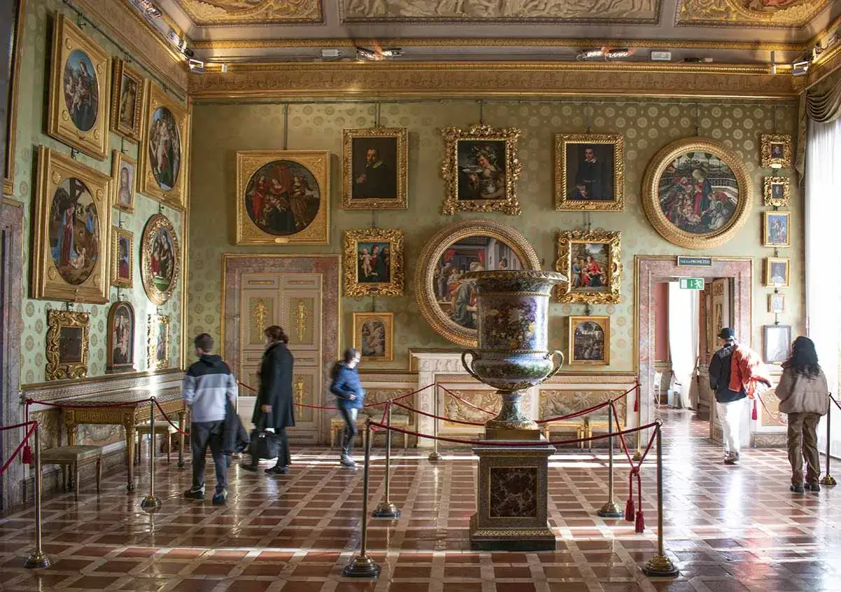 Interno di una sala del Palazzo Pitti, con opere d'arte alle pareti e un grande vaso decorato al centro.