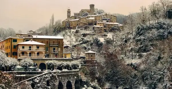 Borgo innevato in Toscana. Case antiche e alberi coperti di neve creano un paesaggio fiabesco, dimostrando che sì, a volte fa neve in Toscana.