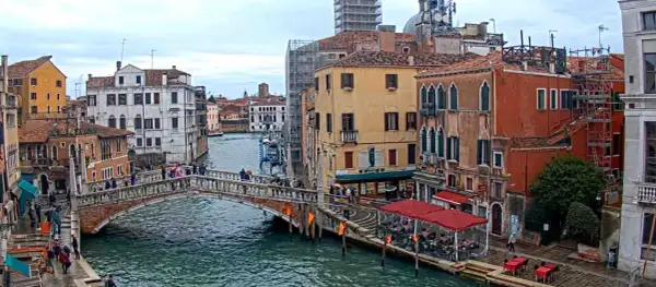 Il ponte delle Guglie attraversa un canale veneziano, circondato da edifici storici e persone che passeggiano.
